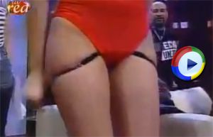 Cute girl removes her panties from under her red swimsuit