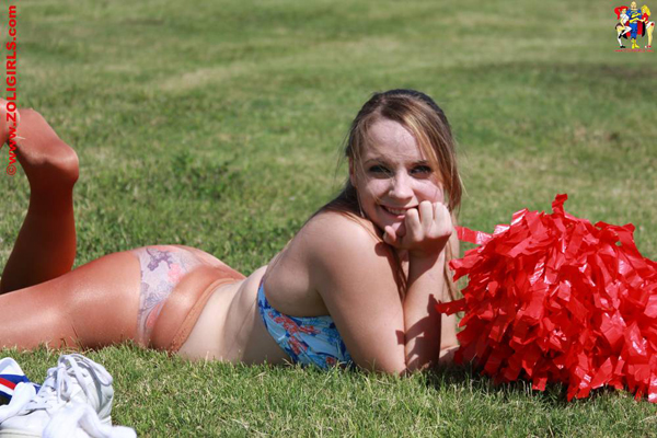 Cute cheerleader lying down on the grass in her underwear and pantyhose