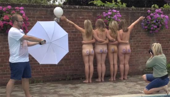 Four naked girls pose by a wall