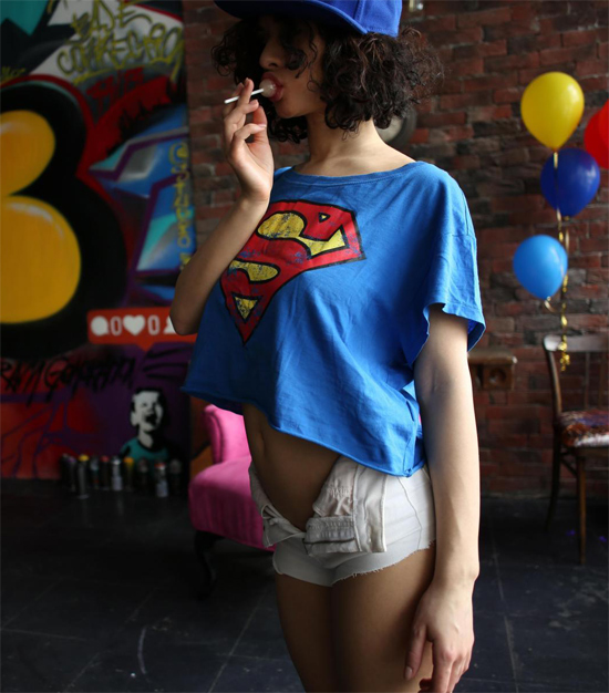 ShpitsyQ in a supergirl top on StasyQ, sucking on a lollipop