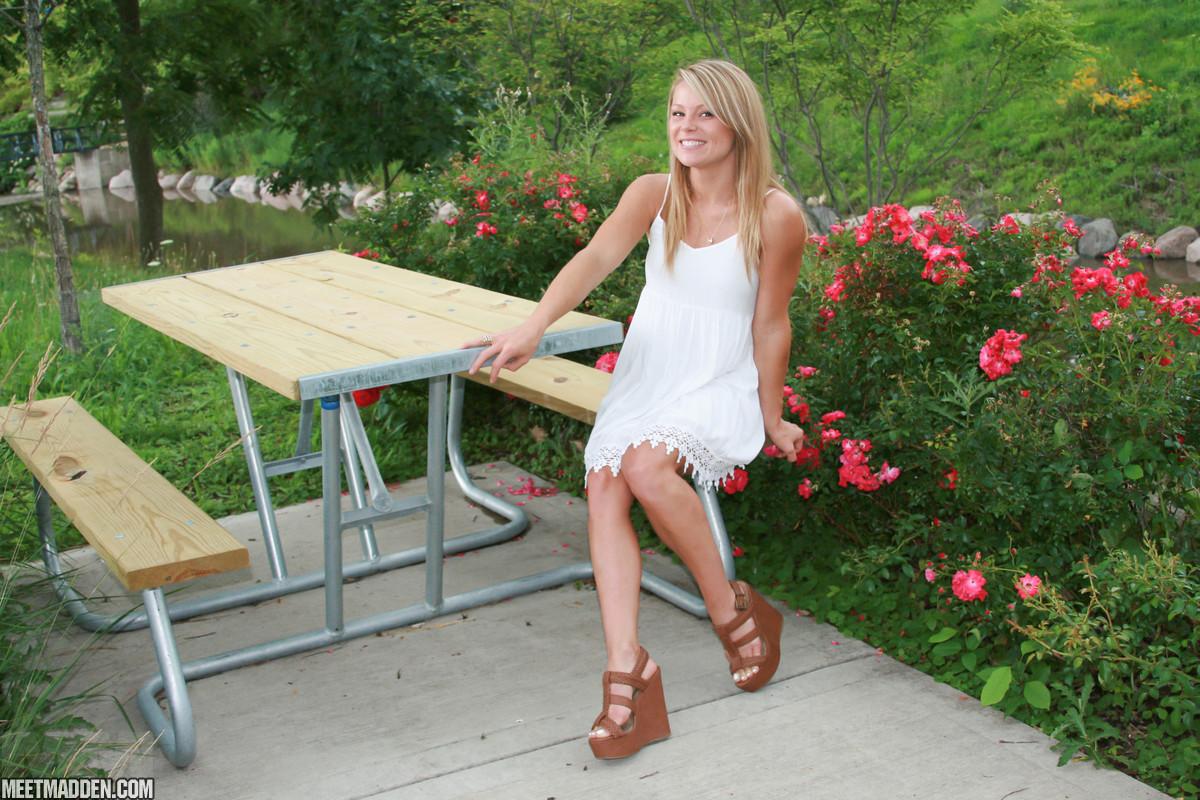 Meet Madden sitting at a picnic table in a white dress