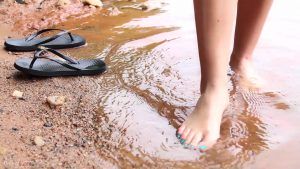 She shows her bare feet as she paddles in the water