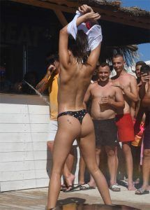 Girl strips topless in public, wearing just her bikini bottoms