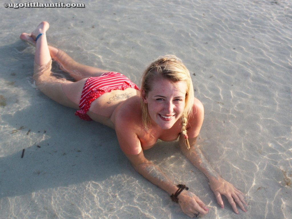 Girl having fun topless on the beach in just her red bikini bottoms